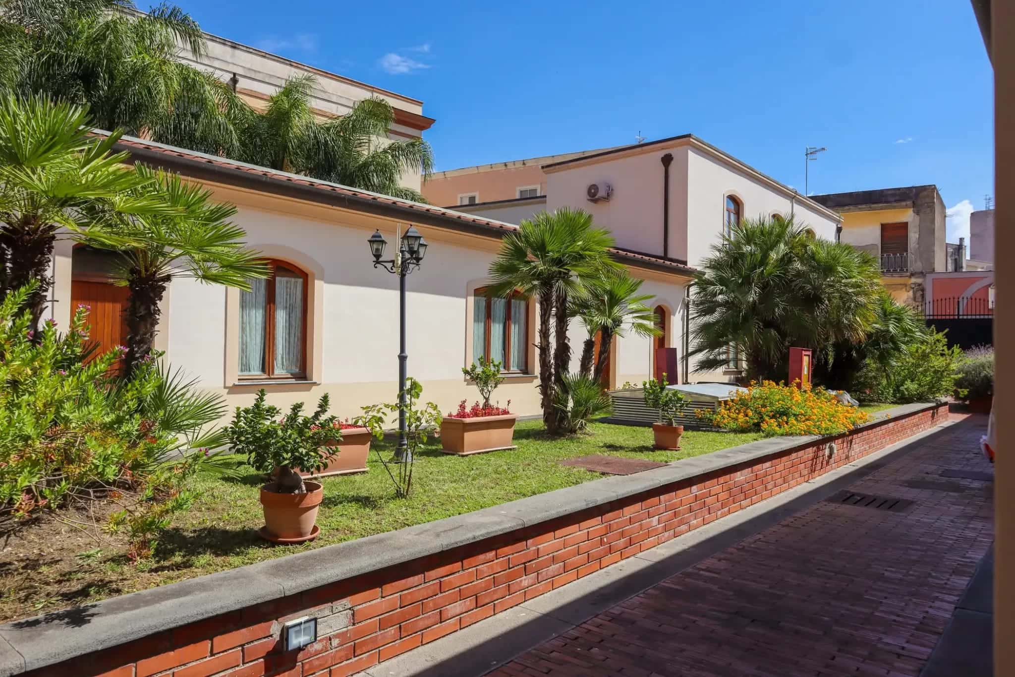 Cortile interno del Pompei Hostel Deluxe con palme e facciata al sole